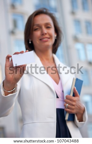 Beautiful businesswoman with visit card across office