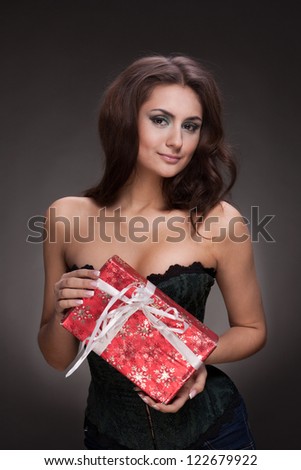 Portrait of brunette beautiful woman with gift on grey background
