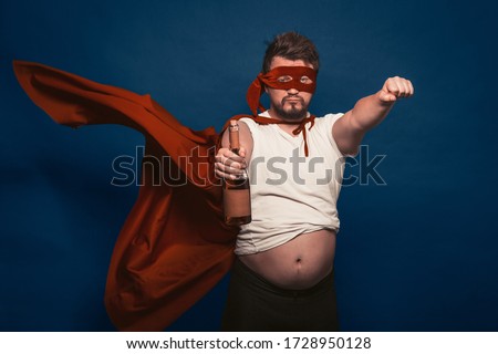 Tipsy Or Drunk Superhero Holding Bottle Of Wine, Man In Superhero Costume Ready For Feats Figuratively Holding Bottle Of Wine In One Hand Shows A Fist With The Other Hand Cut Out On Blue Background Foto d'archivio © 