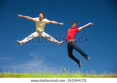 Two young people jump on top of hill in park