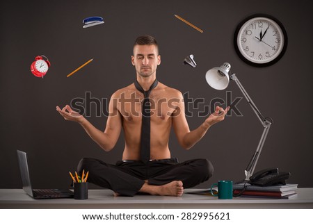 Naked yogi businessman relax in office, while his work is doing. Handsome businessman sit on table in office in lotus position and try to relax.