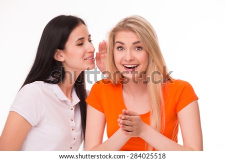 Girlfriends talking about funny moments of life. Girl in orange T-shirt put her hands together.