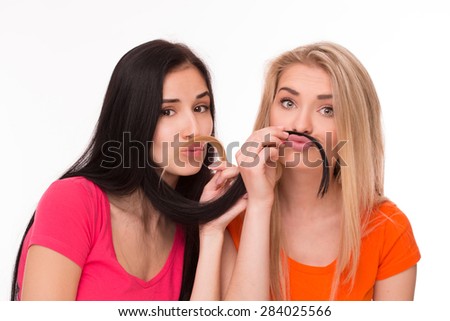 Young pretty blonde and brunette posing like hipsters. Girls in pink and orange T-shirts looking funny.