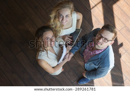 Real estate representatives smiling after having grand deal with man. Women carrying documents and a tablet PC.