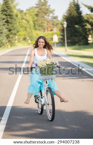 Girl wearing stylish clothes having fun outdoors. Young pretty beautiful woman riding her white retro hipster bike.