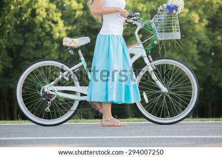 Close-up of young girl walking. Young girl in blue skirt walking on the street with retro bicycle.