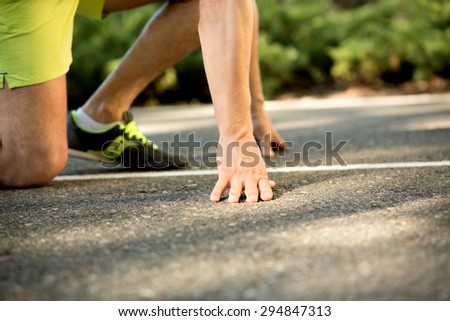 Close-up of fitness runner before jogginf. Man in yellow shorts and grey trainers ready to start his race.