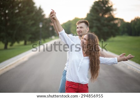 Happy couple having fun moments of their life. Man touching his girl-friend\'s hands and smiling in beautiful sunset.
