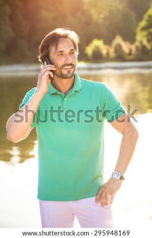 Portrait of happy businessman talking on mobile in the air. Fashionable and rich man smiling with his business partners.