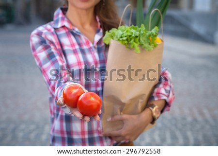 Close-up of two tomatoes in woman\'s hand. Lady demonstrating tomatoes from the bag in her hand.