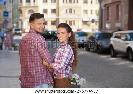 Young couple in a candid shot. Beautiful people in summer clothes walking in the street of European country.