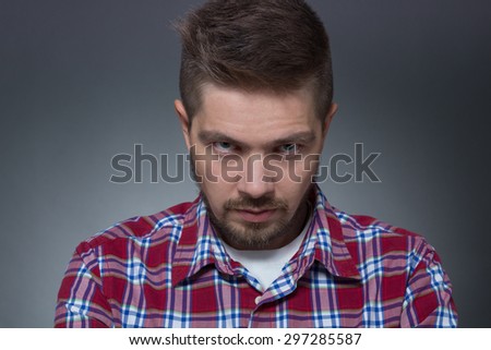 Profile of handsome man pinking. Short-haired model in plaid shirt looking stonily at photographer in photostudio.