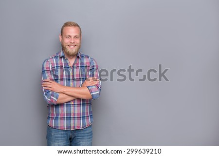 Portrait of smiling bearded man with short haircut. Middle-aged man posing with his arms crossed on grey background.