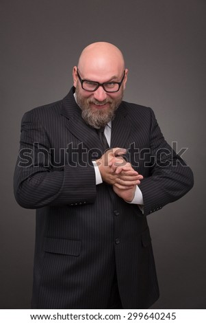 Profile of hipster bearded businessman in glasses. Bold man in black business suit grinning with delight on dark background.