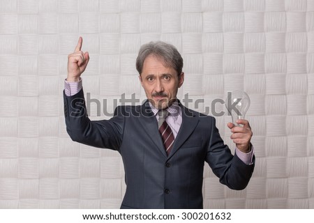 Businessman pointing out isolated on cream background. Mature man in grey business suit knows how to rule the company and be successful.