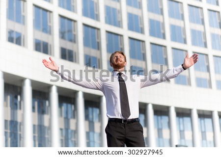 Successful businessman celebrating with arms up. Man in white shirt with tie looking at the sky and happy smiling.