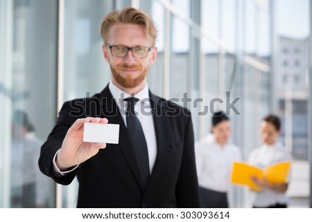 Portrait of young businessman in glasses showing a visit card. Man representing blank card isolated on his collegues.