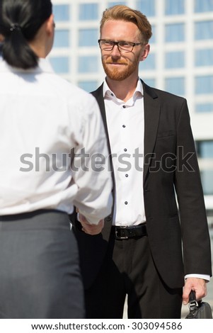 Business handshake of two people. Smiling businessman in black business suit giving a handshake to close the deal.