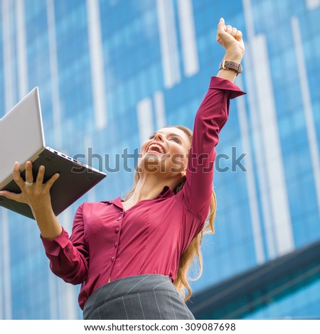 Happy businesswoman celebrating success of her company isolated on office building background. She is the winner in the deal between two companies.