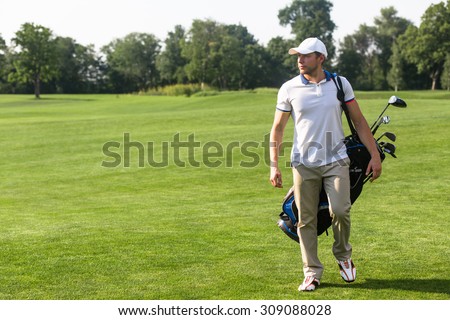 Golf and golfer concepts. Golf player in  trucker hat walking and carrying bag with golf clubs on course during summer time.