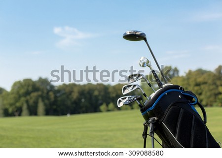 Golf clubs over green field background. Bunch of golf clubs in the bag over blue sky background. Have a nice vacation in summer!