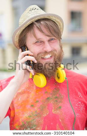 Hipster bearded man speaking over the phone. Freelancer man communicating with his partners and looking at the camera.