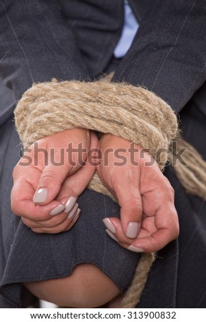 Woman\'s hands are tied up hands with strong rope corresponding to big problems in her company or enterprise.