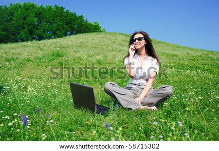 Beautiful young woman with notebook and mobile phone sit on hill
