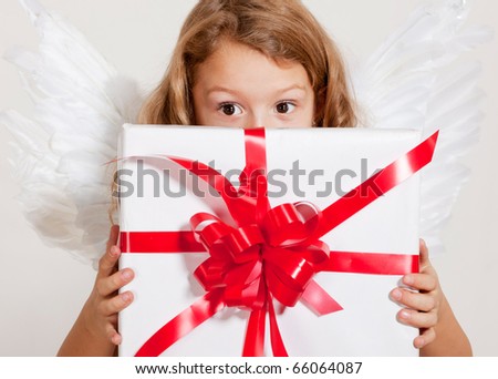 Young girl with angel wings and set of gifts in studio