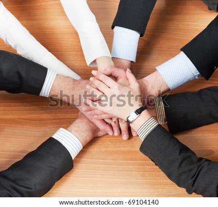 Office workers hold hands together on table