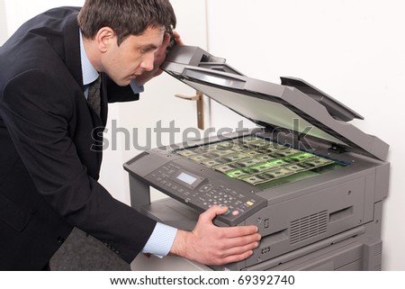 Businessman make false money on copy machine in office