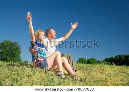 Couple, man and woman take a rest on hill in park