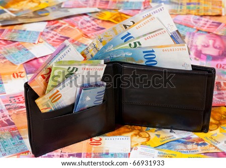 A Wallet with Swiss Francs in it, standing on a Floor with other Swiss Francs Banknotes