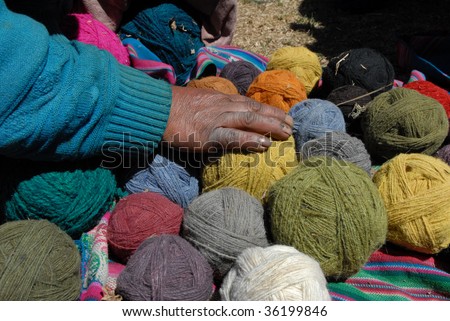 PERU - CIRCA SEPTEMBER 2007: A local Peruvian woman touches balls of weaved colored cloth circa Sept 2007 in Peru. The color comes from plant extracts and animals, leaves & roots.