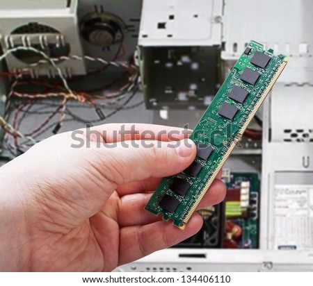Hands holding PC RAM against the system unit