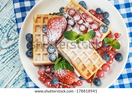 Waffles with fresh berries on the table. Focus on the strawberry and mint. small depth of field