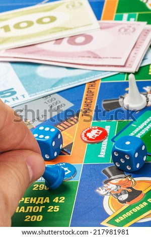Moscow, Russia - September 11, 2014: Monopoly game on the table. Monopoly game in Russian, a board game in the genre of economic strategy for two or more people. Focus on the counter in his hand