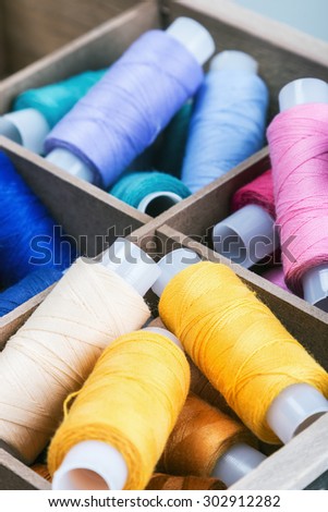 multicolored threads in wooden box. focus on yellow Threads