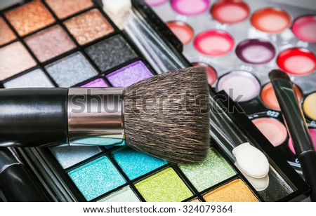 Make-up colorful eyeshadow palettes with makeup brushes. Focus in the bottom of the frame on the blue shadows. Shallow depth of field