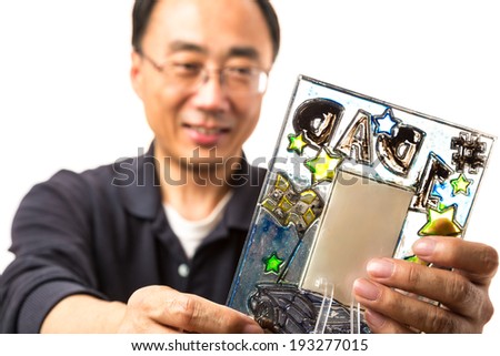 Asian man looking at a picture frame from his son on Fathers day