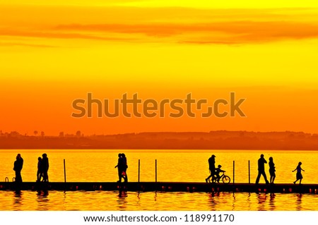 Group of people walking on boardwalk at sunset