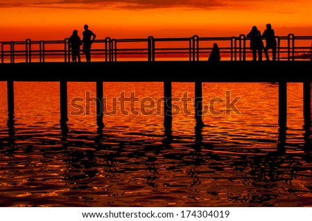 Group of people silhouette on boardwalk at sunset