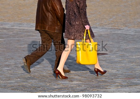 Fashionable woman with yellow bag walking with man