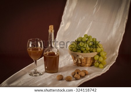 Still life with grapes, glass, organic wine bottle and walnuts