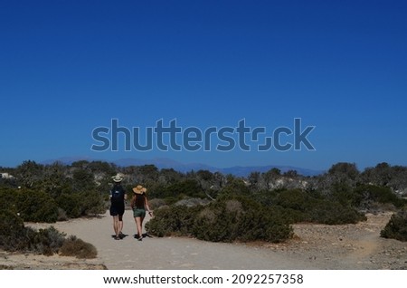 Tourist pair walking on the island of Chrissi, Greece. Distant mountains, seen on the horizon, are situated on another island, Crete, located 15 km from here.