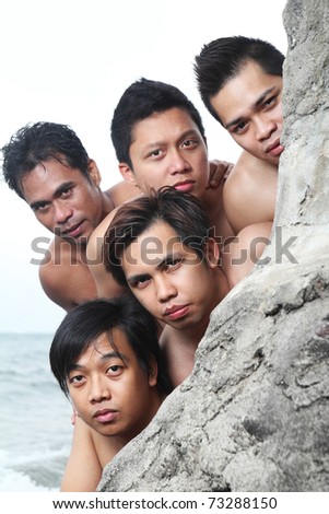 Group of asian men looking over the wall by the sea