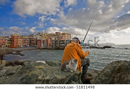 an old fishermen fishing in Boccadasse, Genoa, Italy, with cat waiting for a quick and free lunch