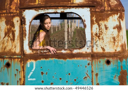 Young woman in old, rusted model of bus