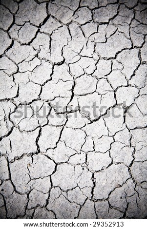 A textural, close-up image of sandy desert ground cracked by the heat and lack of water.