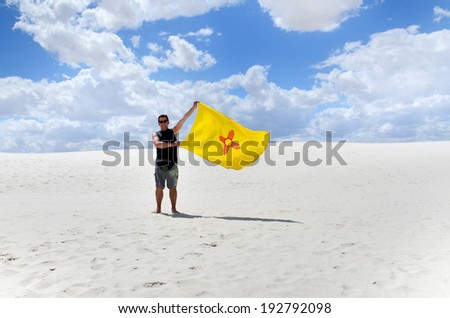 WHITE SANDS NM USA APRIL 24: Man waving New Mexico flag in White Sands National Monument  the largest gypsum dune field in the world. On april 24 2104 in White Sands NM USA